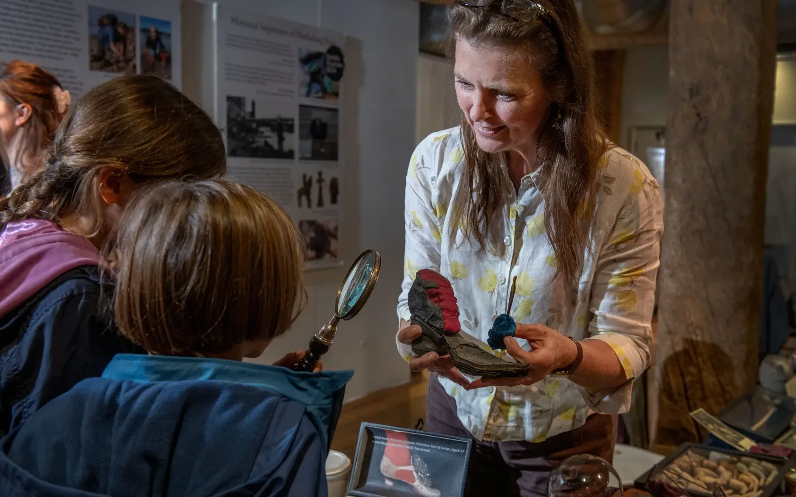 Visitors examine a Thames mudlarking find with a magnifying glass at London Museum Docklands
