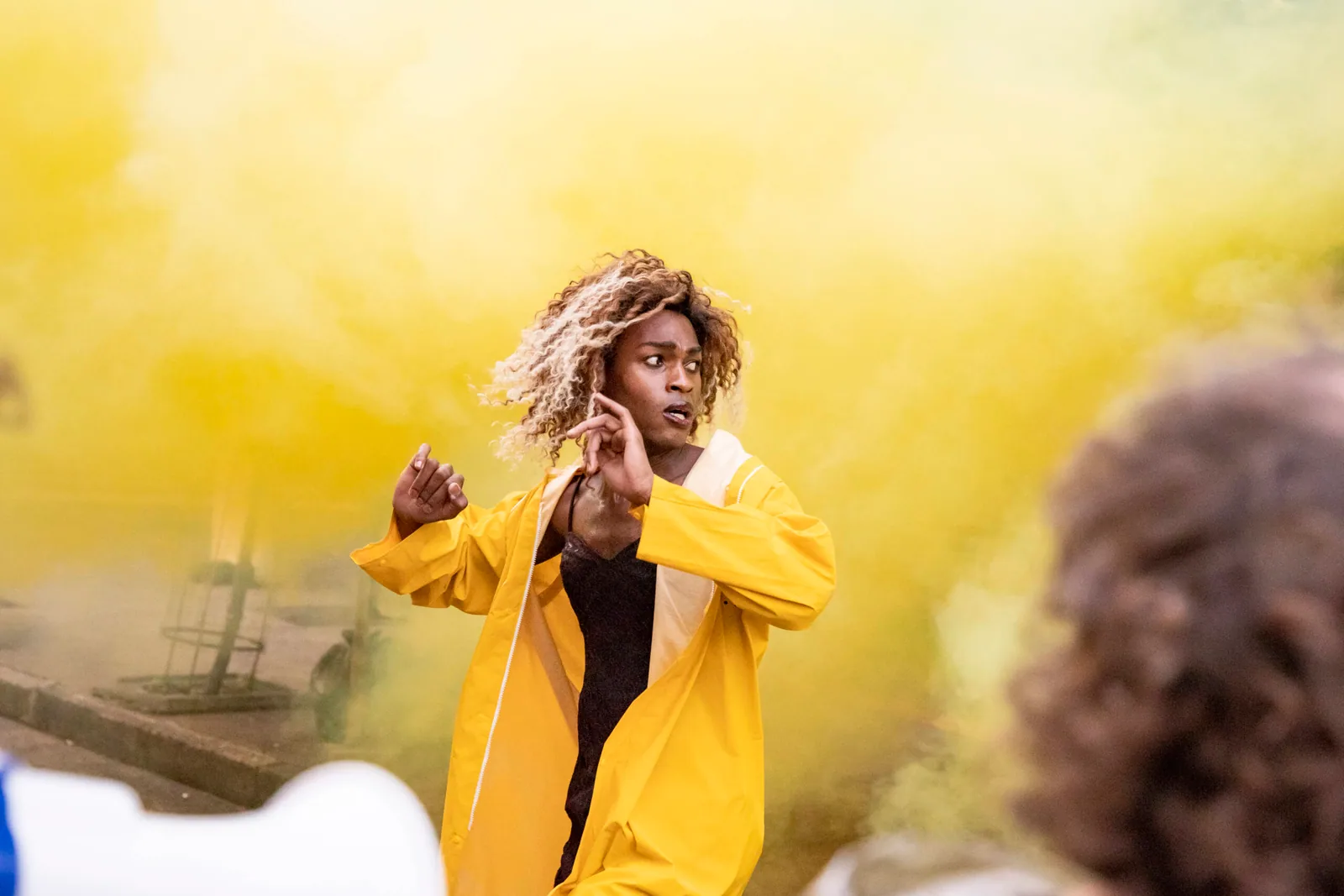 A performer in a yellow coat moving through smoke in Efectos Especiales