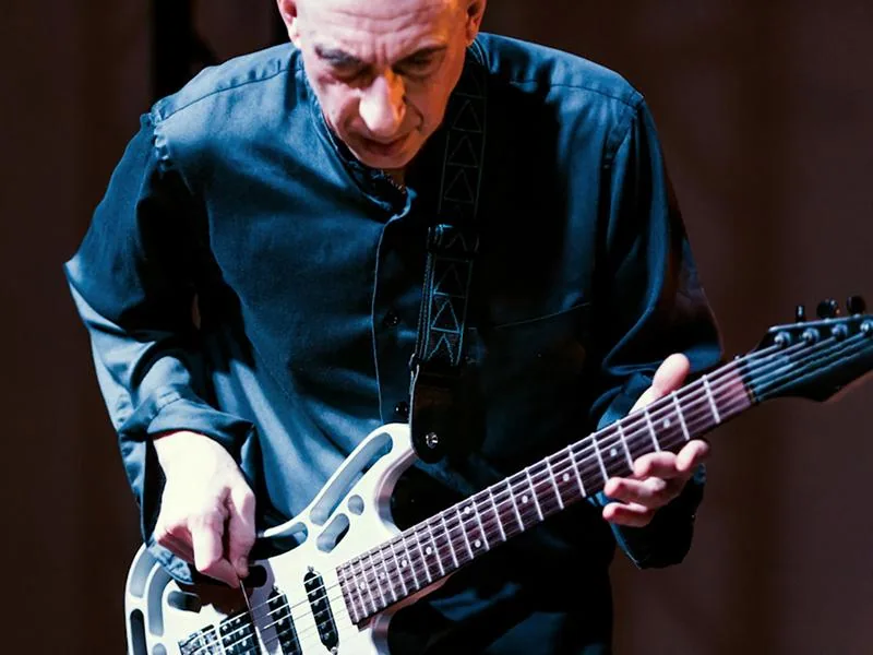 Experimental composer and guitarist Elliott Sharp performing under blue stage lights