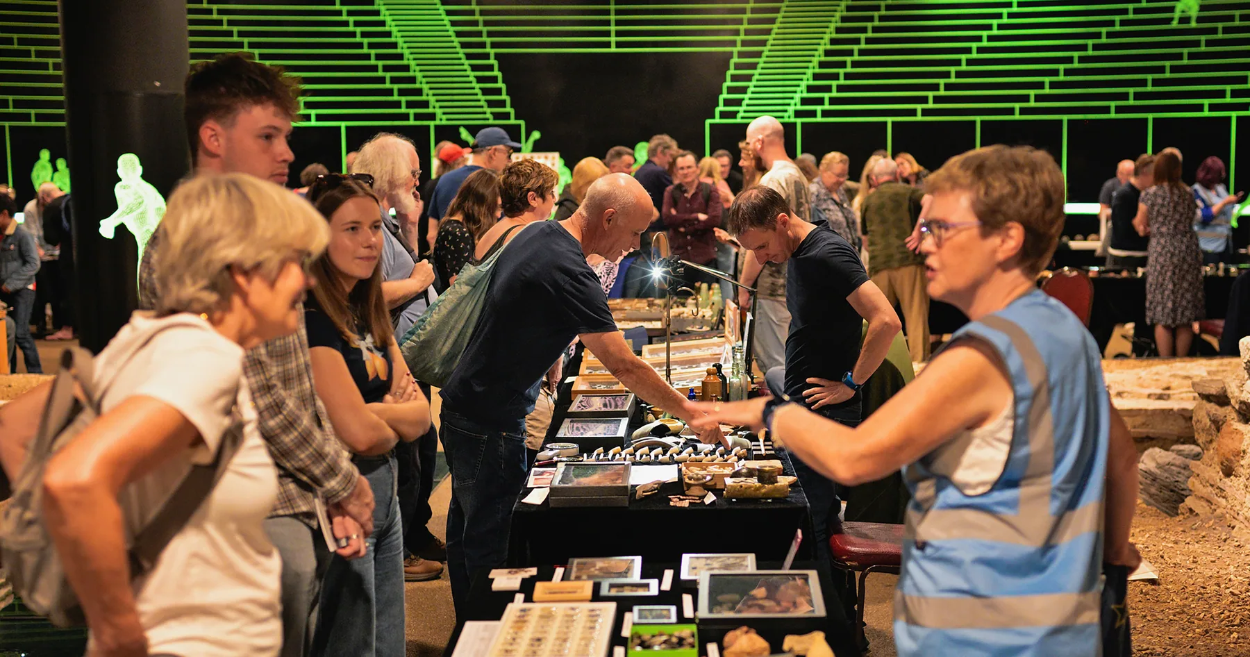 Visitors examining Thames-found artefacts at a mudlarking exhibition in the Roman amphitheatre