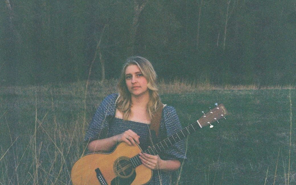 Andrea von Kampen holding an acoustic guitar outdoors